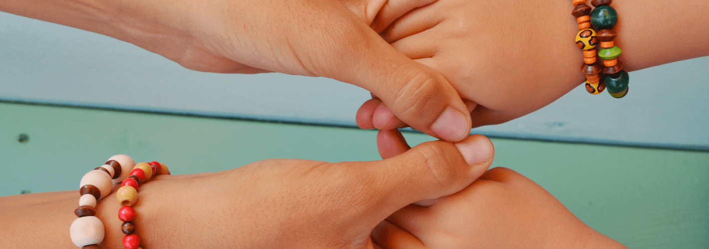 Photo d'une main d'un enfant de sa maman avec des bracelets en bois.